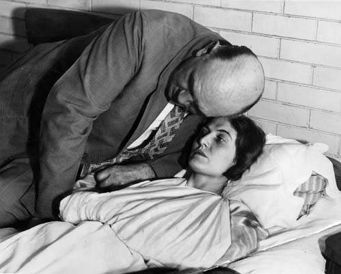 Winnie Ruth Judd whispers to her husband, Dr. William C. Judd, as she lies ...